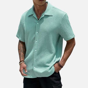 Camisa de meia abotoadura em cor sólida, com caimento solto e design versátil, ideal para ocasiões casuais e sociais.