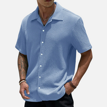 Camisa de meia abotoadura em cor sólida, com caimento solto e design versátil, ideal para ocasiões casuais e sociais.